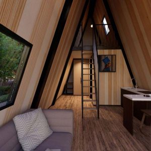 Enterijer A-Frame kućice sa modernom kuhinjom, drvenim zidovima, udobnim dnevnim boravkom i galerijom do koje vode crne metalne stepenice.